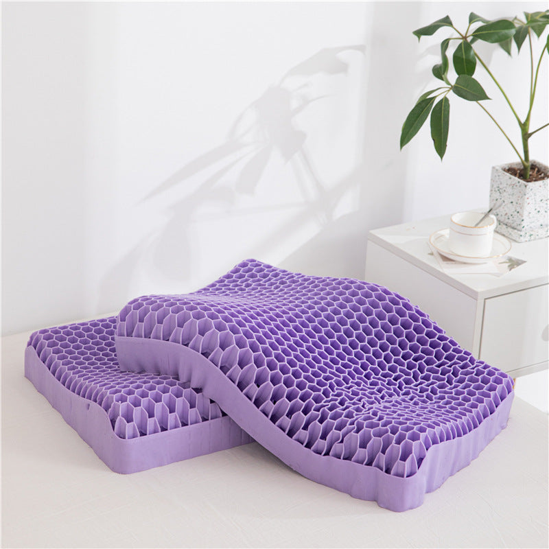 Two Cloud Dreams Neck Message Bed Pillow 3D cushions, in a soothing purple honeycomb gel design and perfect for alleviating discomfort from cervical spondylosis, rest on a white surface beside a potted plant and a small table with a cup and saucer. These cost-effective solutions add comfort and style to your space.
