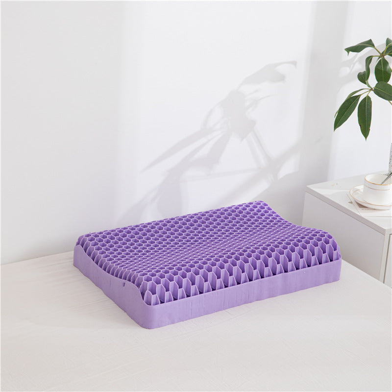 A cost-effective, purple honeycomb-patterned Neck Message Bed Pillow 3D by Cloud Dreams is placed on a white bed next to a nightstand with plants in the background.